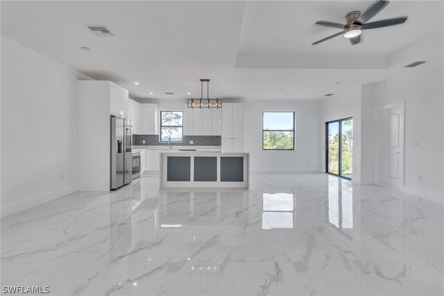 interior space featuring pendant lighting, a kitchen island, light tile floors, white cabinets, and stainless steel fridge with ice dispenser