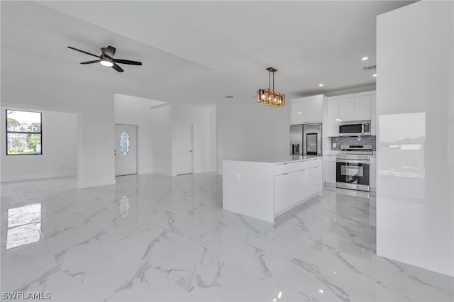 kitchen with appliances with stainless steel finishes, white cabinetry, light tile flooring, and pendant lighting