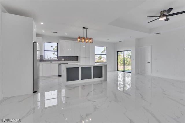 kitchen featuring a healthy amount of sunlight, a kitchen island, light tile floors, and decorative light fixtures