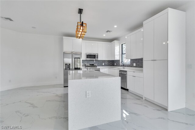 kitchen featuring decorative light fixtures, a kitchen island, white cabinetry, appliances with stainless steel finishes, and light tile floors