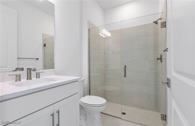 bathroom with a shower with door, vanity, and toilet