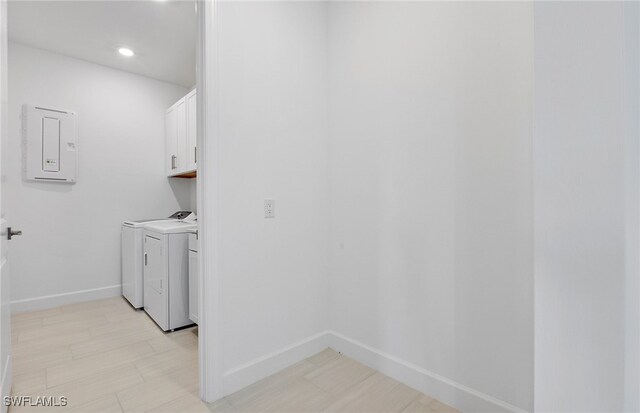 laundry room with washer and dryer, cabinets, and electric panel