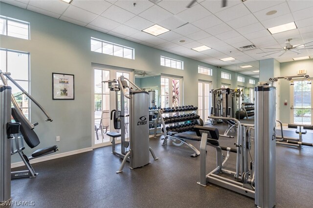 exercise room featuring a paneled ceiling, a high ceiling, ceiling fan, and a wealth of natural light