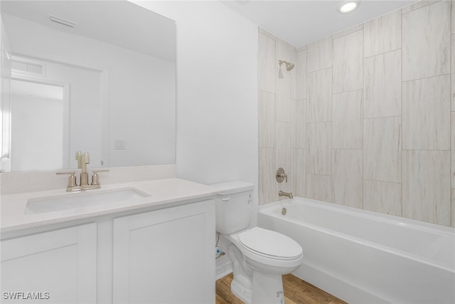 bathroom with toilet, wood finished floors, visible vents, vanity, and washtub / shower combination