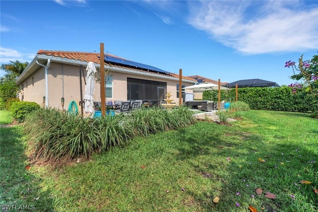 back of property featuring solar panels and a lawn