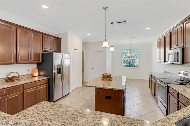 kitchen featuring light stone countertops, appliances with stainless steel finishes, decorative light fixtures, a kitchen island, and ornamental molding