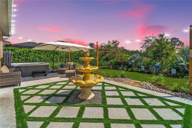 patio terrace at dusk featuring a hot tub