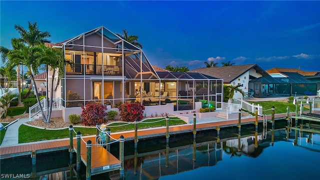 rear view of house featuring a balcony, a water view, a lanai, and a yard