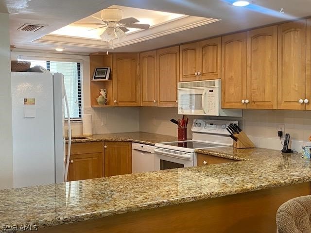 kitchen with light stone counters, white appliances, visible vents, a ceiling fan, and a raised ceiling