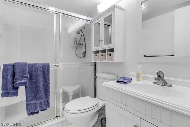 bathroom featuring vanity, toilet, and a shower with door