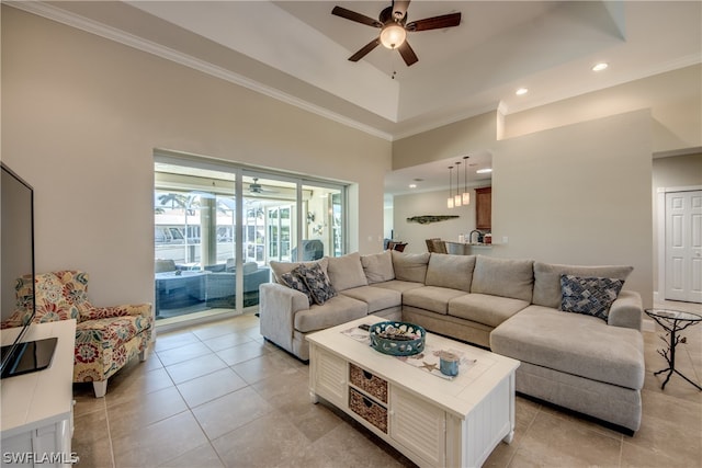 tiled living room with a high ceiling, crown molding, a tray ceiling, and ceiling fan