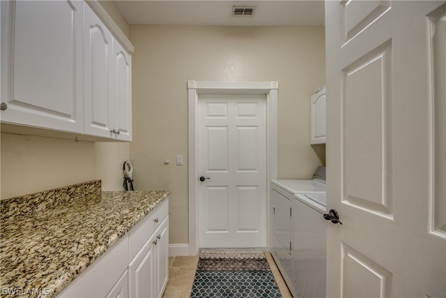 laundry area with light tile floors, cabinets, and separate washer and dryer