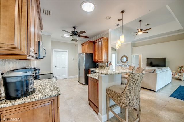 kitchen featuring decorative light fixtures, stainless steel appliances, ceiling fan, and light stone countertops