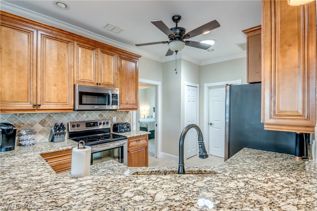 kitchen featuring light stone countertops, ceiling fan, appliances with stainless steel finishes, backsplash, and sink