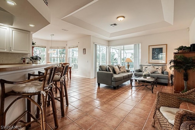 living room with light tile patterned floors and a tray ceiling