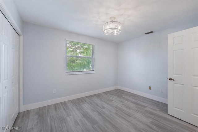 374 Dover Pl Unit 803, Naples, FL 34104 - unfurnished bedroom with a notable chandelier, a closet, wood finished floors, baseboards, and visible vents