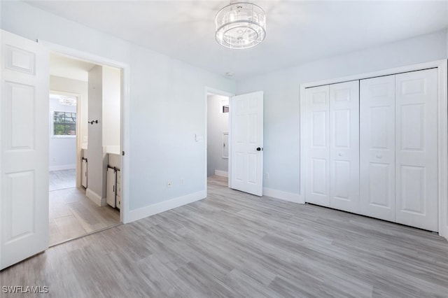 374 Dover Pl Unit 803, Naples, FL 34104 - unfurnished bedroom featuring baseboards, a chandelier, a closet, and light wood-type flooring
