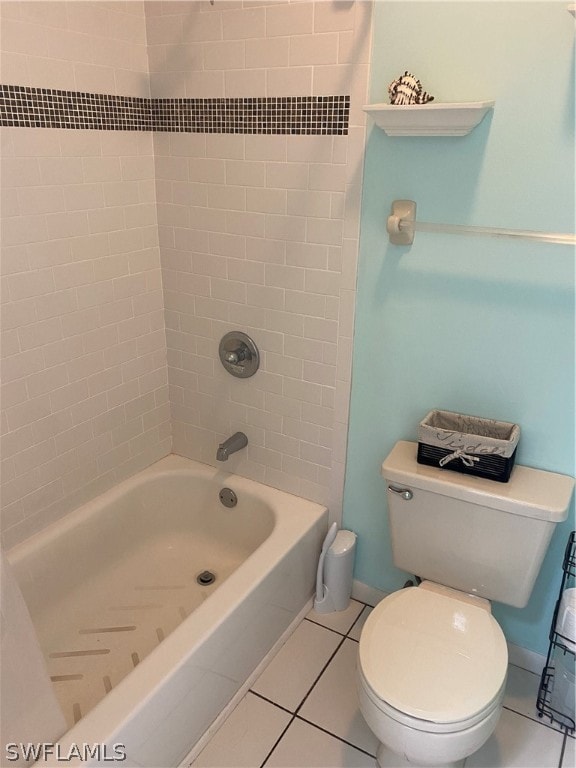 bathroom featuring tiled shower / bath, toilet, and tile flooring