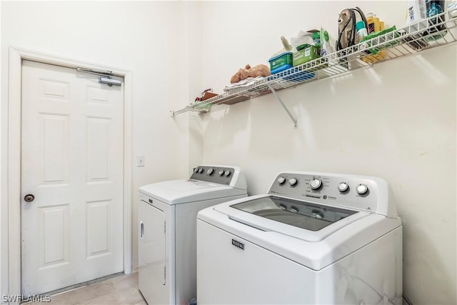 laundry area with washer and clothes dryer and light tile patterned floors