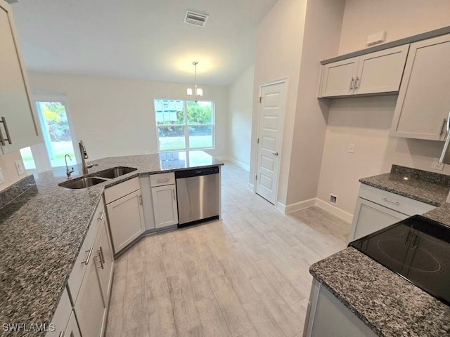 kitchen with light wood-type flooring, stainless steel dishwasher, sink, pendant lighting, and dark stone countertops