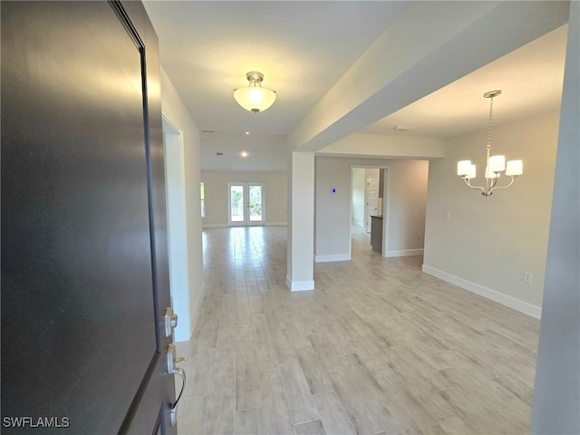 empty room featuring a chandelier, french doors, and light hardwood / wood-style floors