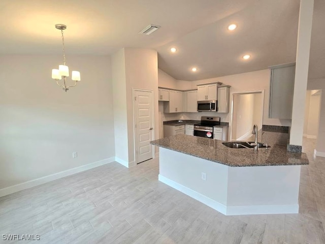 kitchen with kitchen peninsula, stainless steel appliances, sink, a notable chandelier, and dark stone countertops