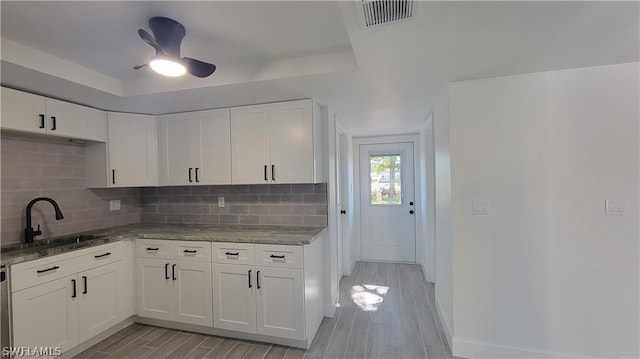 kitchen with backsplash, ceiling fan, white cabinets, and sink