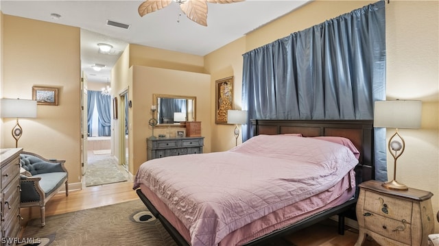 bedroom with ensuite bathroom, ceiling fan, and hardwood / wood-style flooring