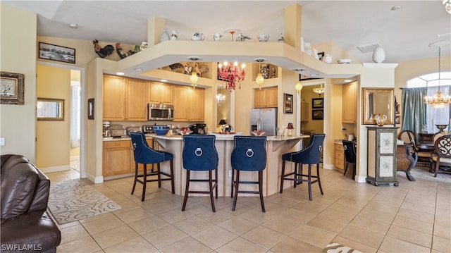 kitchen featuring a breakfast bar, light tile patterned flooring, stainless steel appliances, and a chandelier