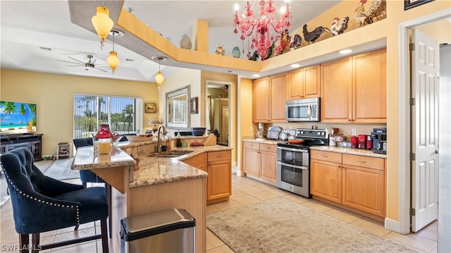 kitchen featuring a large island, sink, stainless steel appliances, and decorative light fixtures