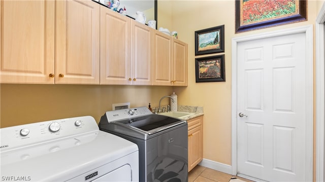 laundry area with cabinets, light tile patterned floors, sink, and washing machine and clothes dryer