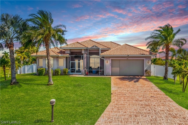 mediterranean / spanish home featuring a sunroom, a garage, and a lawn