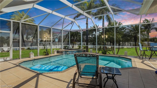 pool at dusk featuring glass enclosure, a yard, an in ground hot tub, and a patio