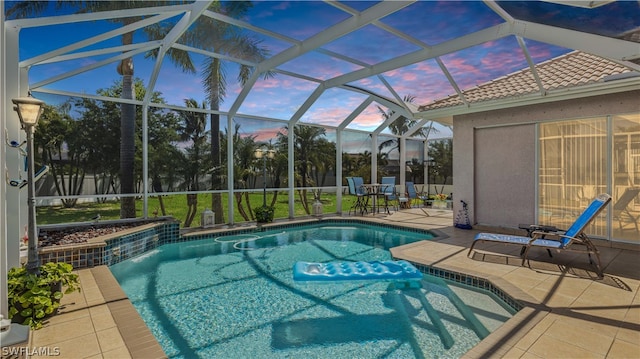 pool at dusk with a patio and glass enclosure