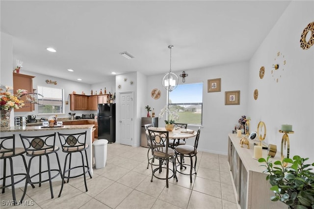 kitchen featuring light tile patterned flooring, a chandelier, kitchen peninsula, and black refrigerator