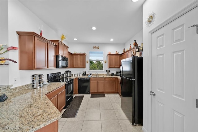 kitchen featuring light stone counters, sink, light tile patterned floors, and black appliances