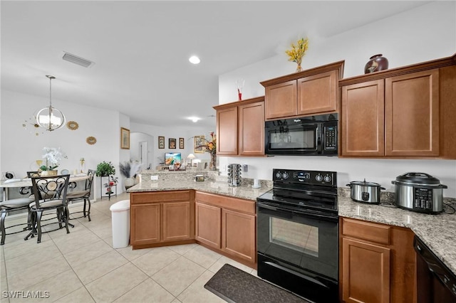 kitchen featuring decorative light fixtures, a notable chandelier, black appliances, light tile patterned floors, and light stone counters