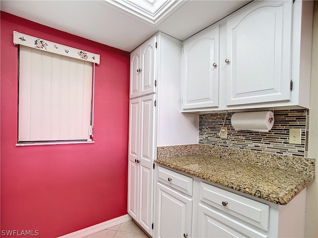 kitchen featuring light tile patterned flooring, white cabinetry, stone counters, and tasteful backsplash