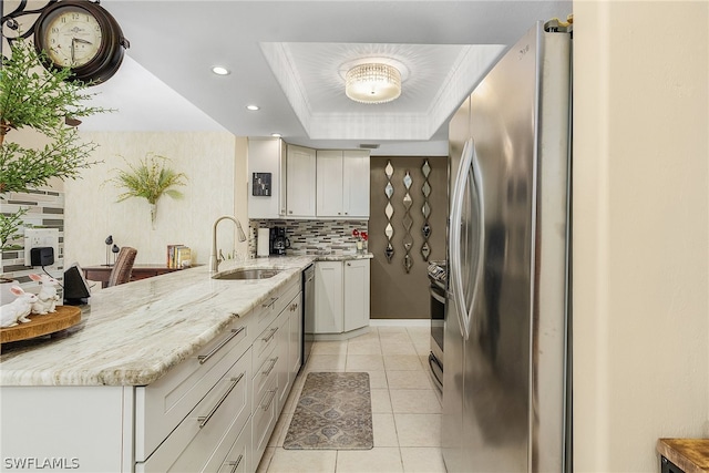 kitchen with backsplash, appliances with stainless steel finishes, sink, light tile floors, and a raised ceiling