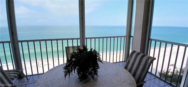 sunroom / solarium featuring a wealth of natural light, a water view, and a view of the beach