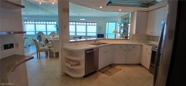 kitchen with open shelves, a peninsula, a sink, stainless steel appliances, and white cabinetry