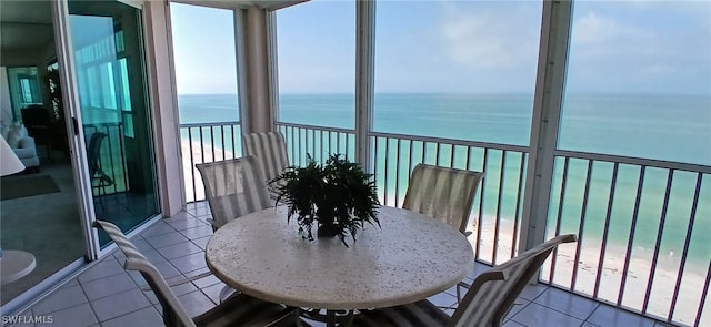 sunroom with plenty of natural light, a beach view, and a water view