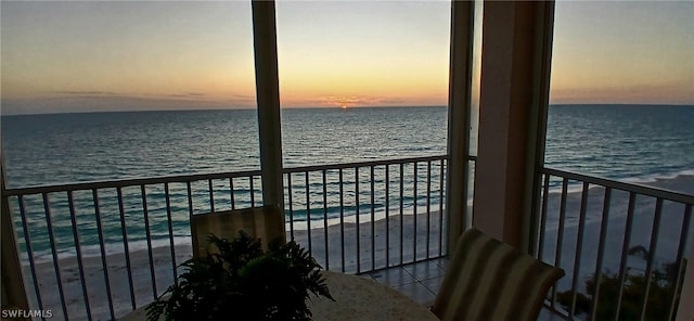 balcony at dusk with a view of the beach and a water view