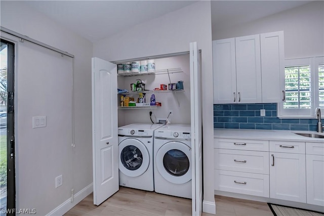 clothes washing area featuring sink, washing machine and clothes dryer, and light wood-type flooring