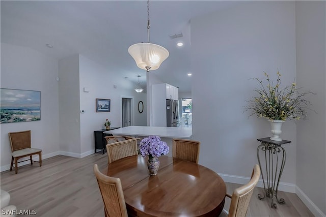 dining room featuring light wood-type flooring and lofted ceiling