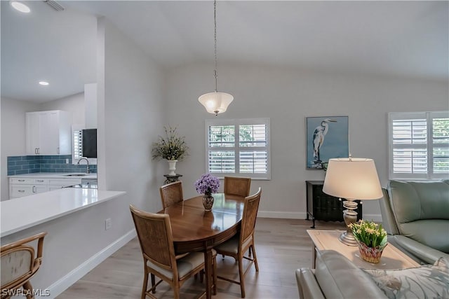 dining area with lofted ceiling, light hardwood / wood-style flooring, and sink