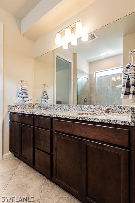 bathroom featuring tile floors, vanity, and tiled shower