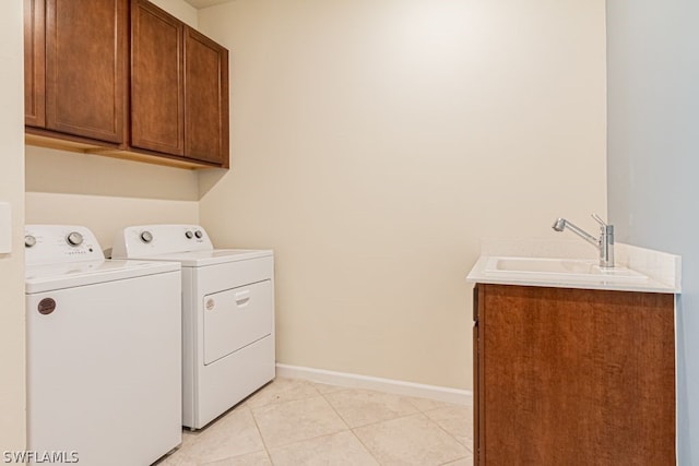 clothes washing area with sink, washer and clothes dryer, cabinets, and light tile flooring