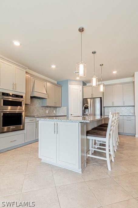 kitchen featuring pendant lighting, tasteful backsplash, stainless steel appliances, and premium range hood