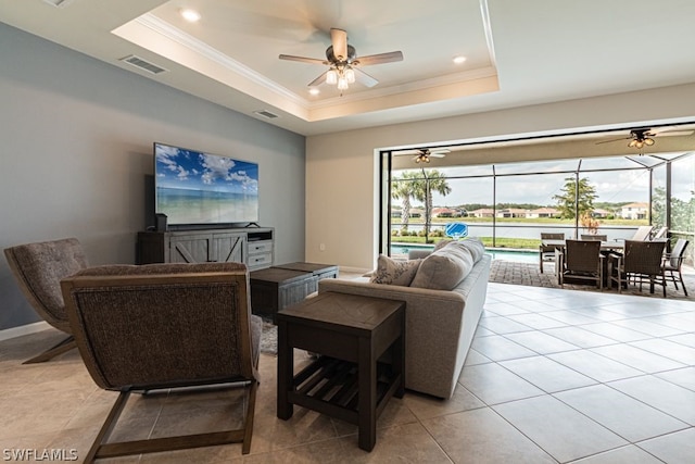 living room with light tile floors, a tray ceiling, and ceiling fan